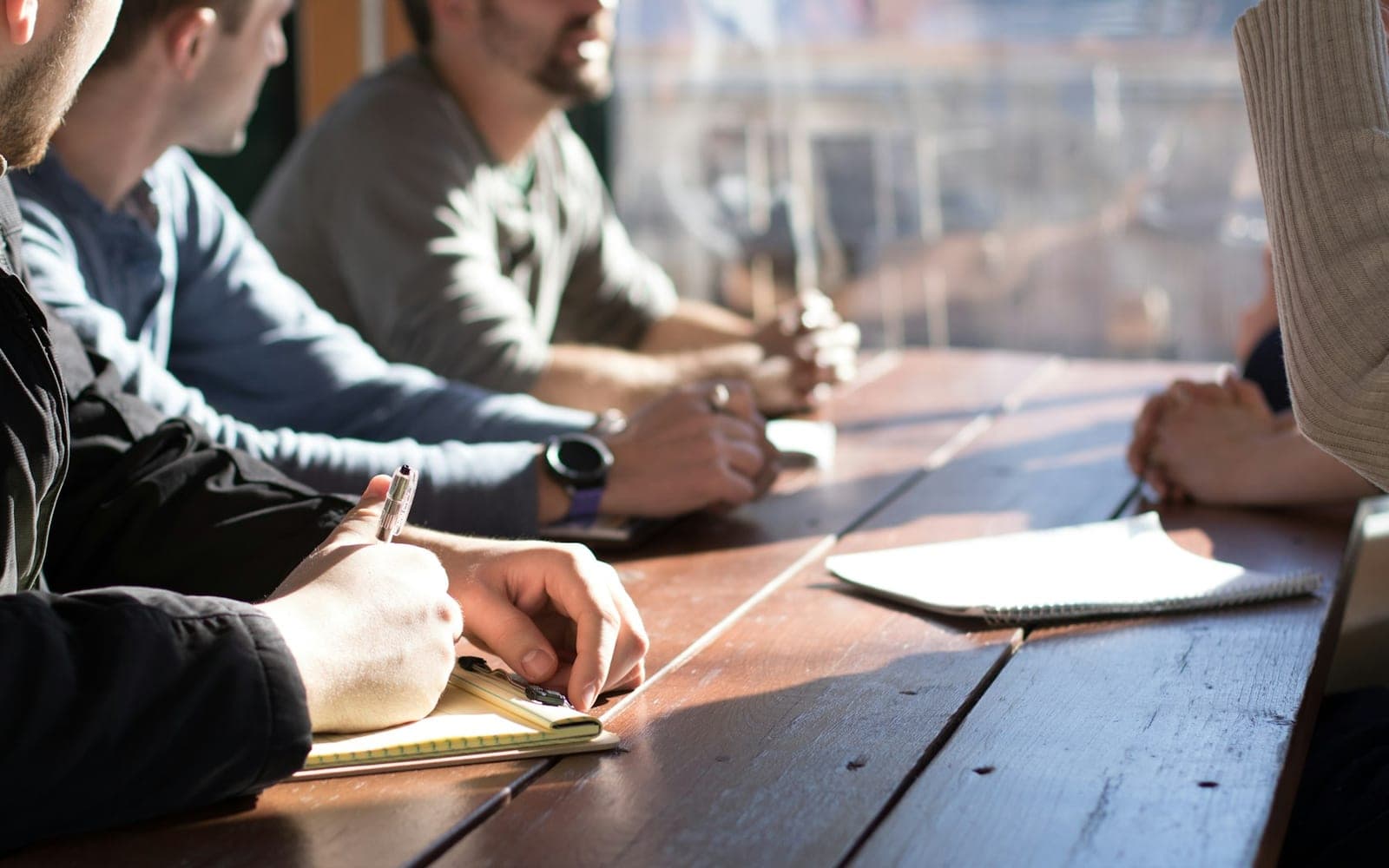 Team seated around a table with notes and pens during a working meeting