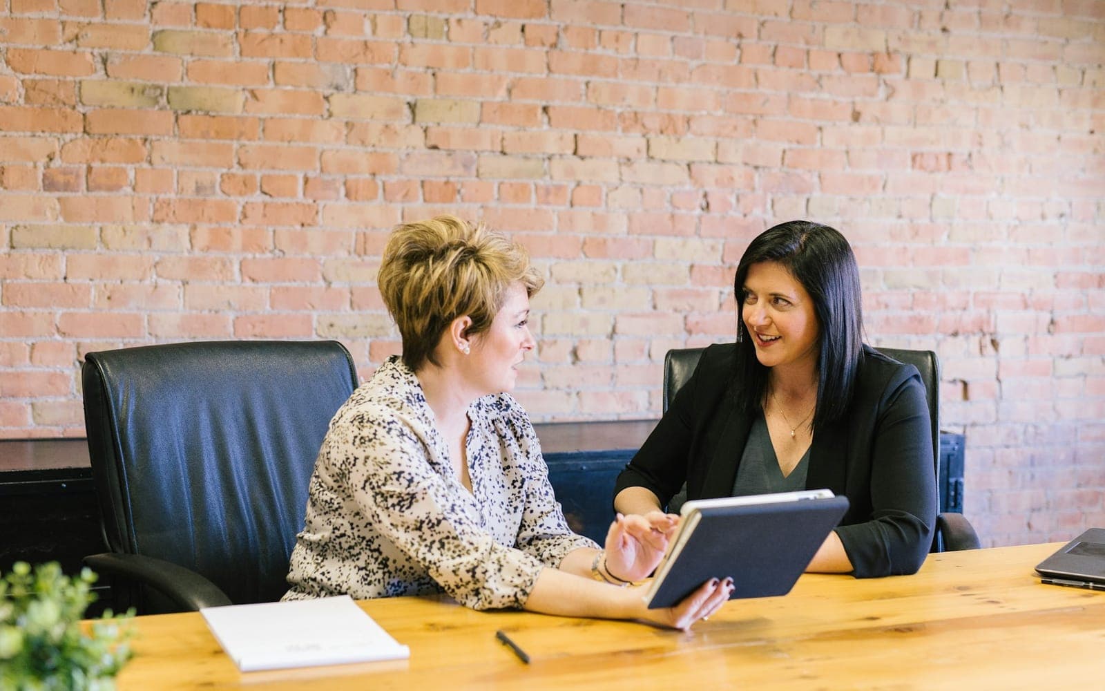 Two professionals collaborating with a tablet during a coordination meeting