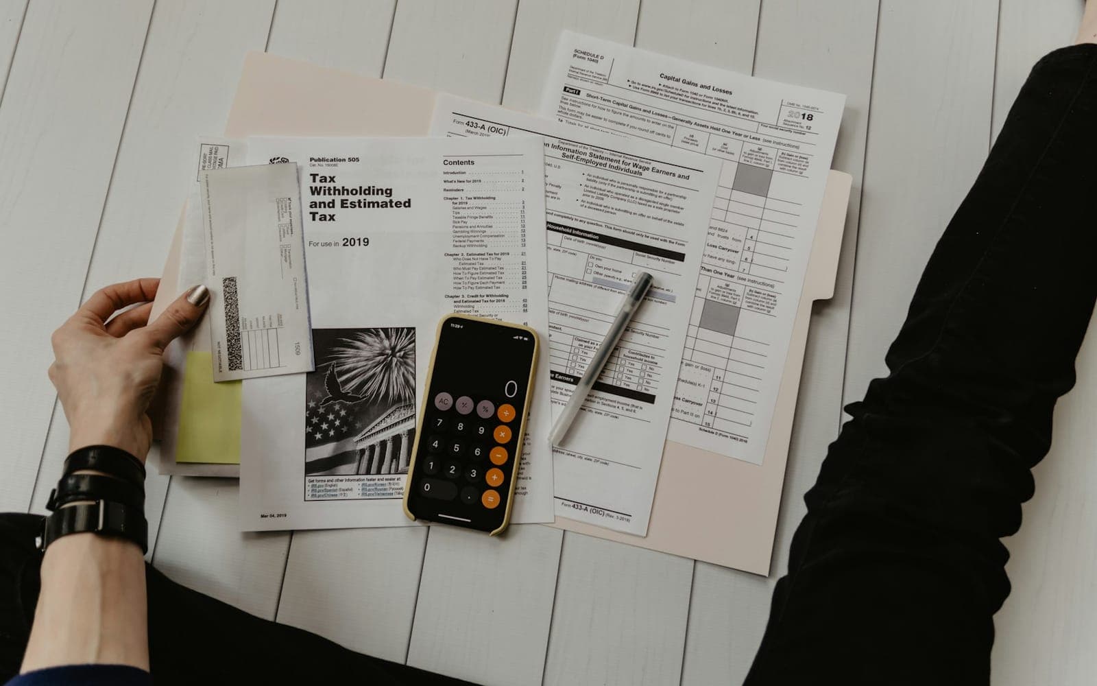 Hand signing formal paperwork beside a calculator