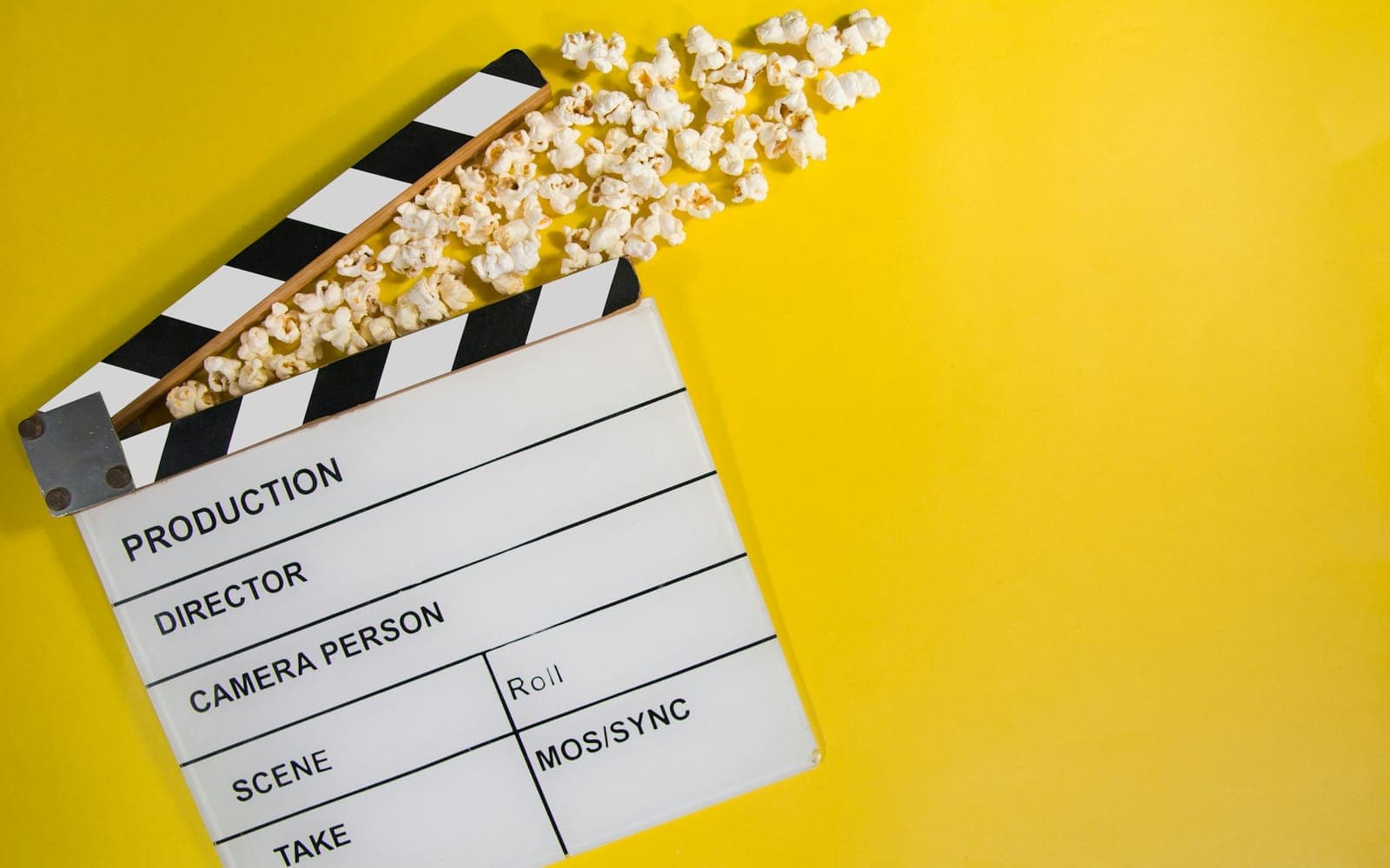 Film clapperboard and popcorn on a yellow background for video production