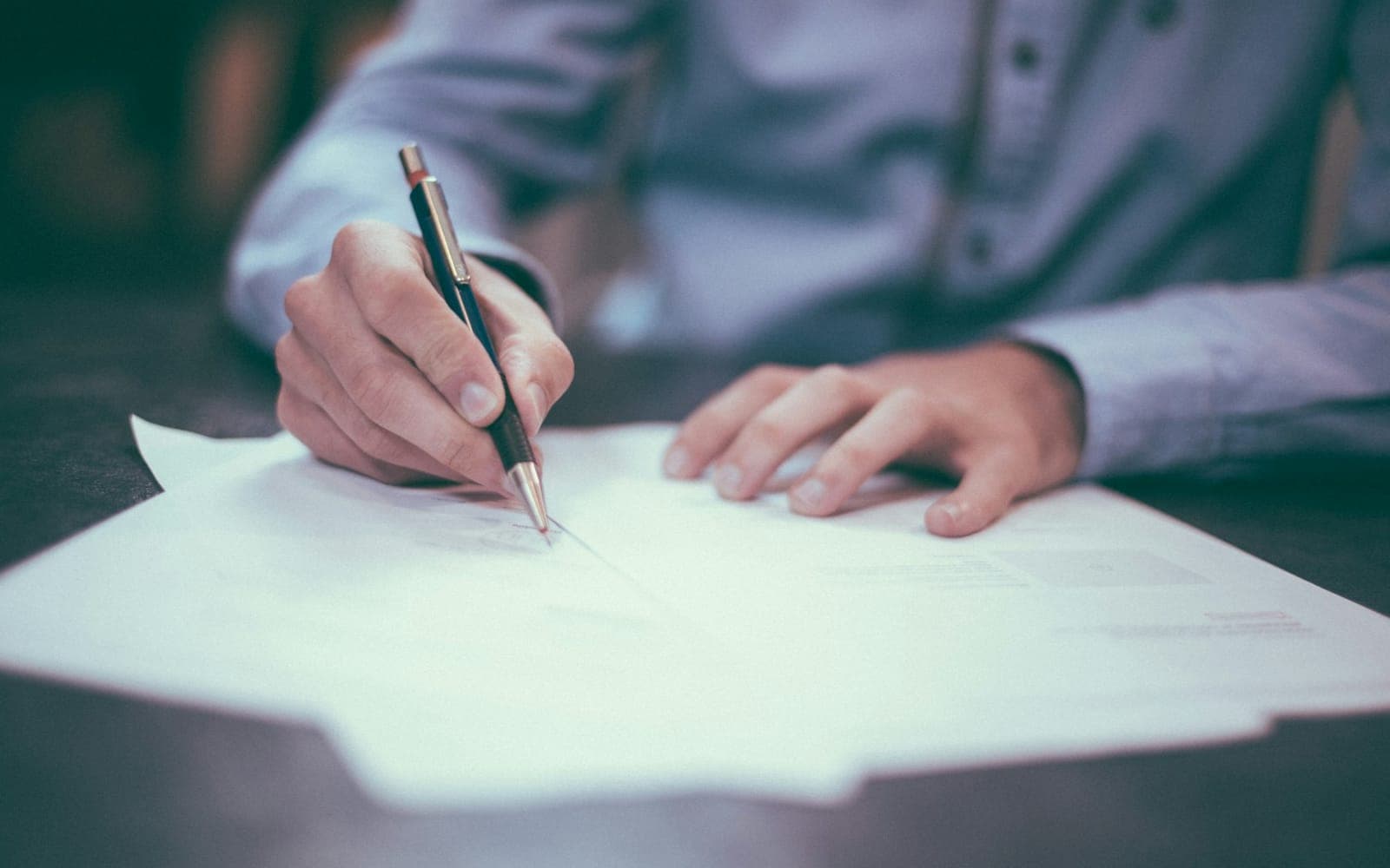 Auditor reviewing stacked documents at a desk with a pen