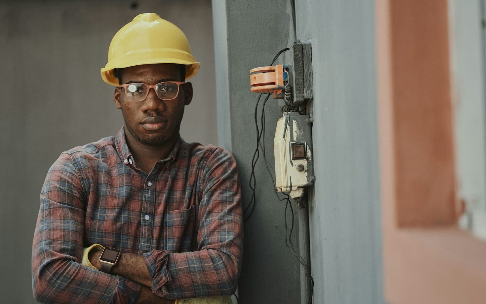 Technician wearing a yellow hard hat beside electrical equipment