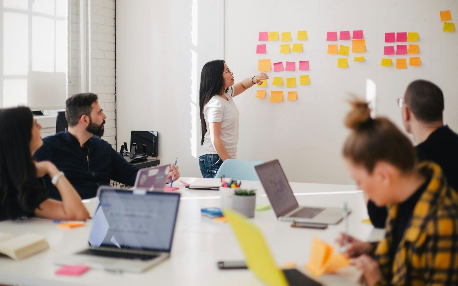 Project team planning around sticky notes on a wall board