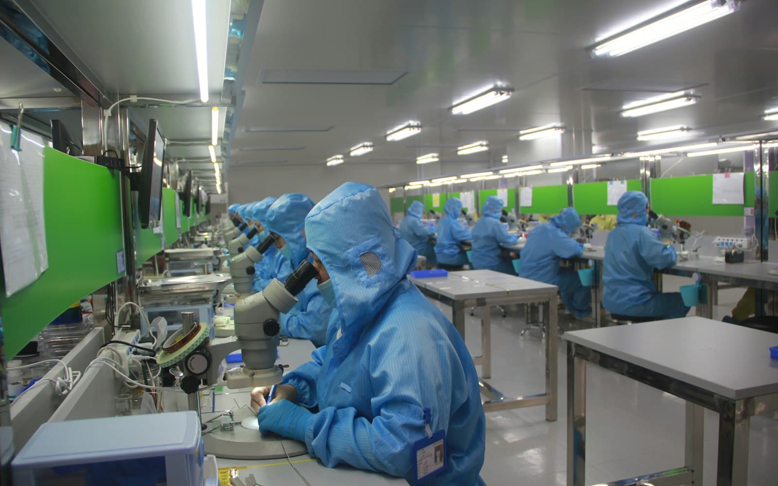 Quality inspectors in clean-room suits checking products on a production floor